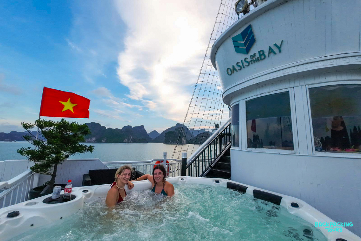 Friends relax in a hot tub on an overnight cruise, surrounded by stunning Ha Long Bay scenery.
