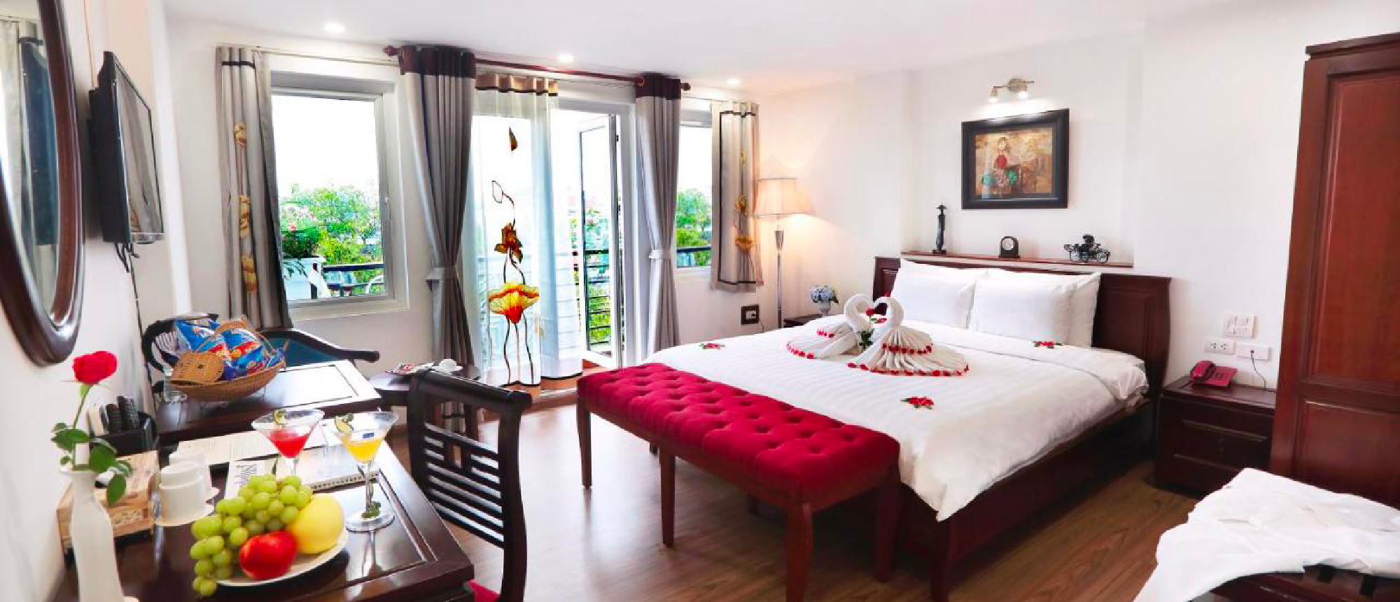 A welcoming hotel room in Hanoi with a comfortable bed, fresh fruit, and a balcony.
